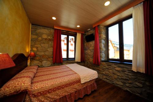 a bedroom with a bed in a room with windows at Hotel Vall d´Aneu in Esterri d'Àneu
