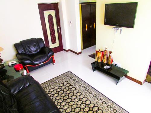 a living room with a black leather chair and a television at Urban Rose Hotel & Apartments in Dar es Salaam