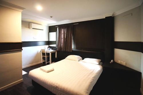 a hotel room with a bed and a desk at HOTEL JJH Aliwal in Singapore