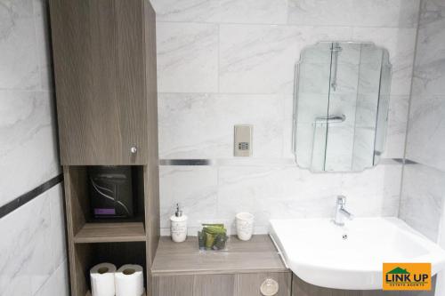 a white bathroom with a sink and a mirror at Holden Court Apartment - Apt 1 in West Drayton