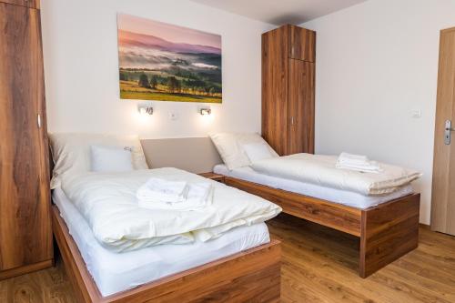 2 camas en una habitación con sábanas blancas en Apartmány Tlustý svišť, en Vaclavov u Bruntalu