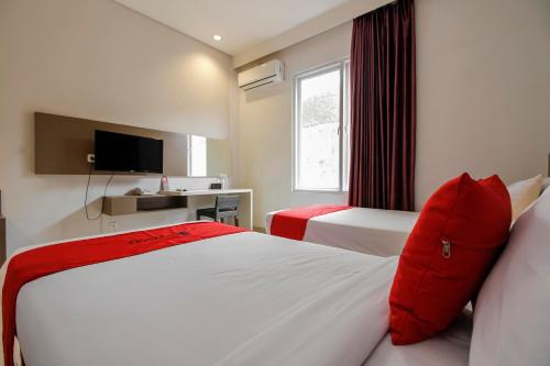 a hotel room with two beds and a television at RedDoorz near Goa Sunyaragi in Cirebon