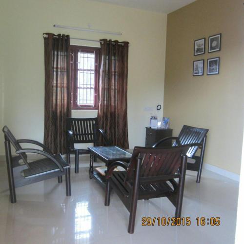 a living room with chairs and a table and a window at Skylarc Inn in Ooty