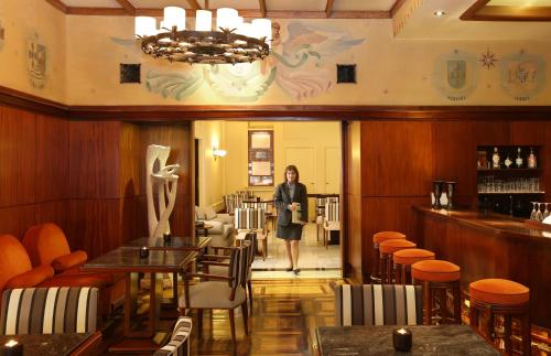 a woman is standing in a restaurant at Hotel Britania Art Deco - Lisbon Heritage Collection - Avenida in Lisbon