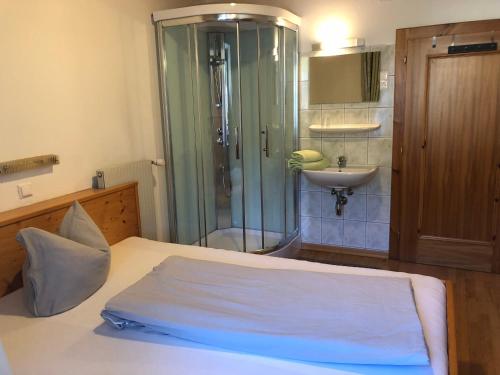 a bedroom with a shower and a bed and a sink at Pension & Ferienwohnung Dullnig in Gmünd in Kärnten