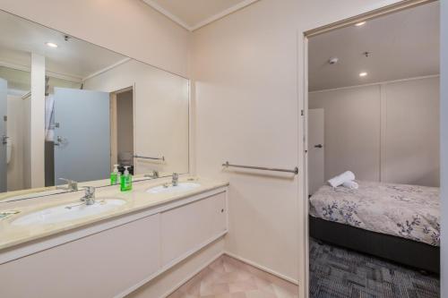 a bathroom with a sink and a bed and a mirror at Riverside Lodge Paihia in Paihia