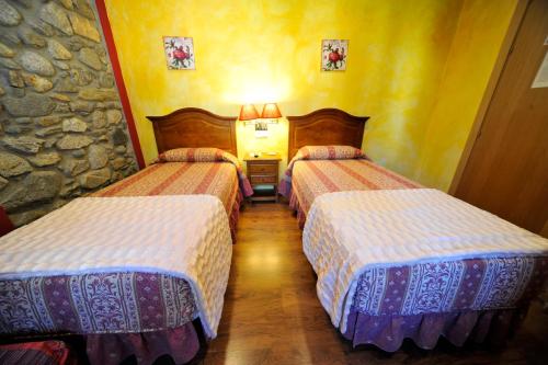 two beds in a room with yellow walls at Hotel Vall d´Aneu in Esterri d'Àneu