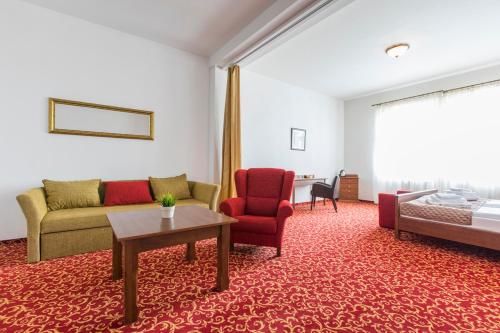a living room with a couch and a bed and a table at Hotel U Zlatého kohouta in Kroměříž