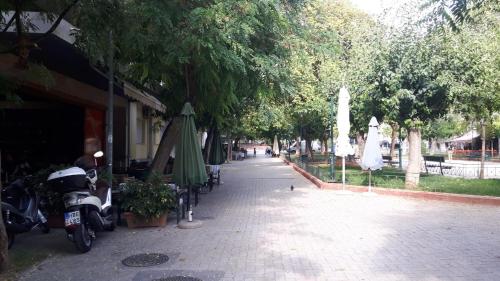un marciapiede con alberi e ombrelloni e una strada di The Cinema Flat ad Atene