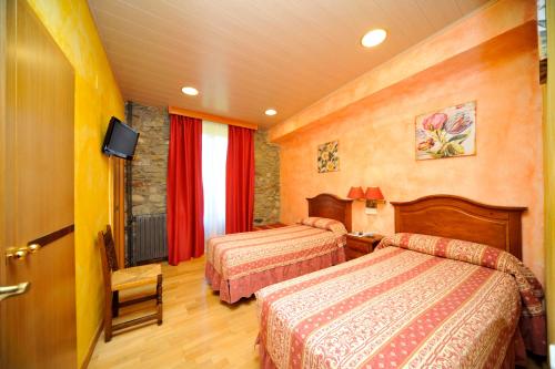a hotel room with two beds and a television at Hotel Vall d´Aneu in Esterri d'Àneu