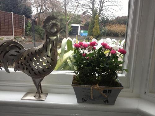 a statue of a chicken and flowers on a window sill at Elmdon Lodge in Birmingham