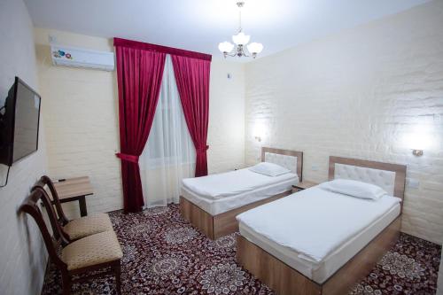 a room with two beds and a chair and a television at Orient Palace in Tashkent