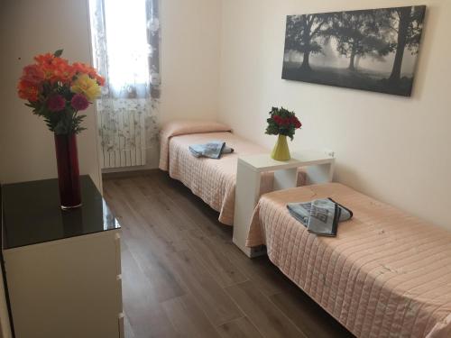 a room with two beds and a vase of flowers on a table at TINTORETTO 1 CON TERRAZZA SOPRA IL TETTO, 3 bagni, 3 grandi camere da letto, SUPER NUOVO in Venice