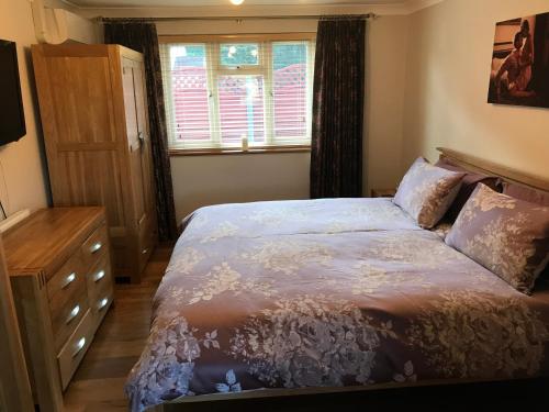 ein Schlafzimmer mit einem Bett, einer Kommode und einem Fenster in der Unterkunft The Bungalow in Billericay