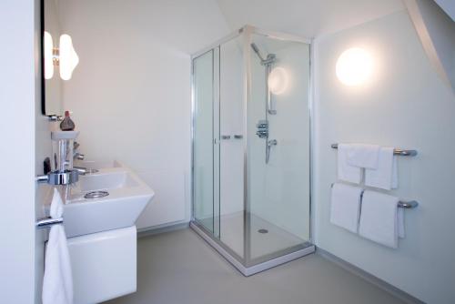 a white bathroom with a shower and a sink at Urban Residences Maastricht in Maastricht
