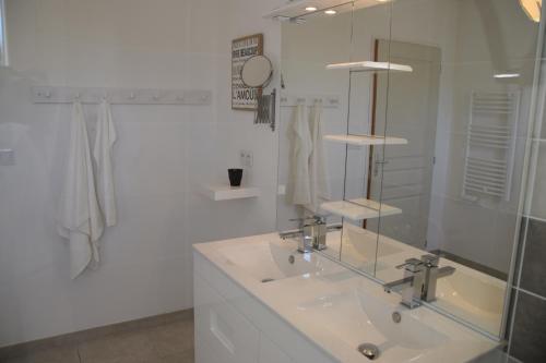 une salle de bain blanche avec un lavabo et un miroir dans l'établissement La maison de Goudargues, à Goudargues