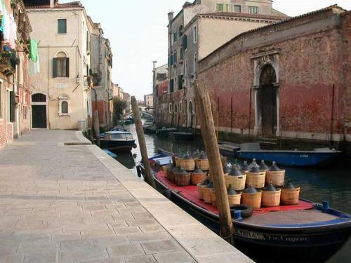 a boat with barrels on it sitting in a canal at TINTORETTO 1 CON TERRAZZA SOPRA IL TETTO, 3 bagni, 3 grandi camere da letto, SUPER NUOVO in Venice