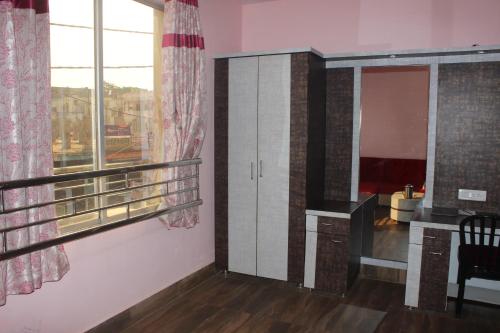 a living room with a large window and a cabinet at Hotel Kwality Inn in Satna
