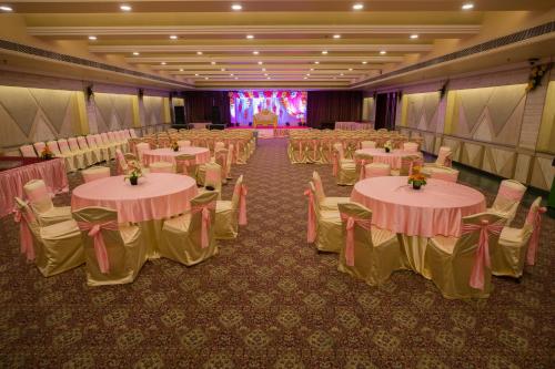 un salón de banquetes con mesas, sillas y un escenario en The Piccadily, en Lucknow