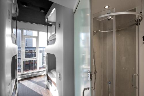 La salle de bains est pourvue d'une douche et d'une porte en verre. dans l'établissement Steel House Copenhagen, à Copenhague