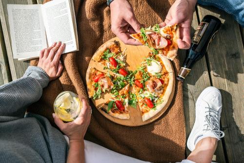 a group of people sitting on a table with a pizza at Hotel Mazurski Raj in Ruciane-Nida