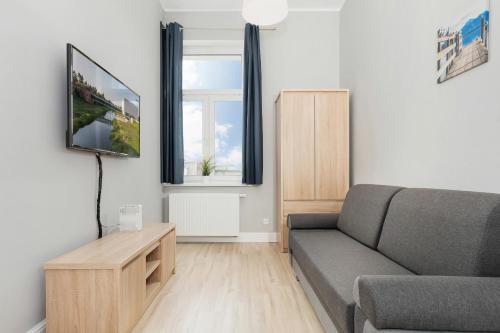 a living room with a couch and a tv at Apartments Poznań MTP by Renters in Poznań
