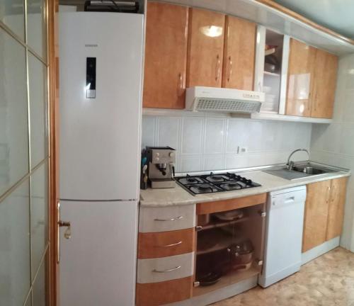 a kitchen with a stove and a white refrigerator at Desconecta a pocos metros de playa y ocio in Los Alcázares