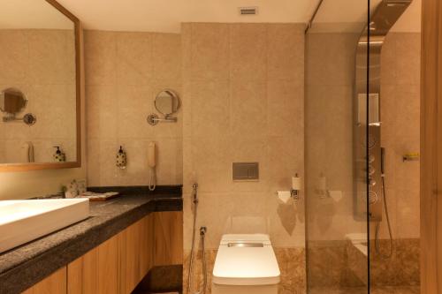 a bathroom with a toilet and a glass shower at Lemon Tree Premier, Patna in Patna