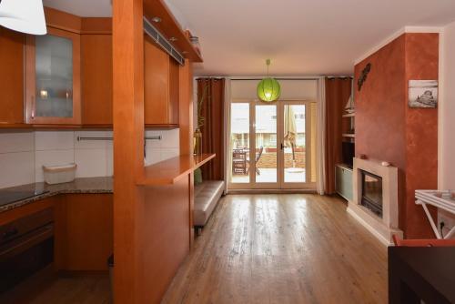 a kitchen with wooden cabinets and a living room at Dunas Flat in Lavra