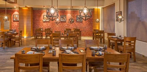 a restaurant with wooden tables and chairs and a brick wall at Lemon Tree Premier, Patna in Patna