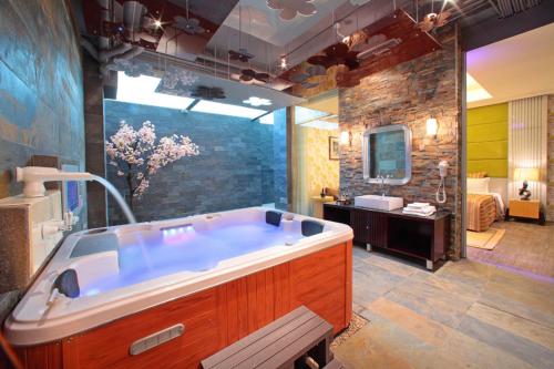 een grote badkamer met een groot bad en een wastafel bij Rainbow Forest Motel in Xiushui