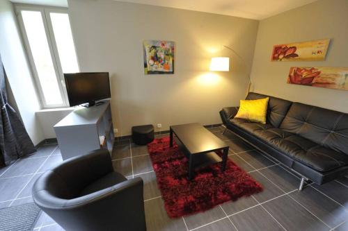 a living room with a black leather couch and a table at Appartement Grande terrasse in La Bourboule