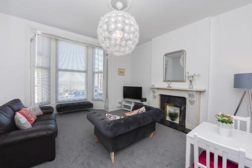 a living room with couches and a chandelier at Spacious one bedroom apartment with a sofa bed offering a sea view sleeps four in Broadstairs