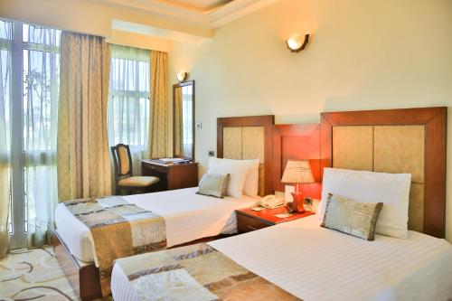a hotel room with two beds and a desk at Swiss Inn Nexus Hotel in Addis Ababa