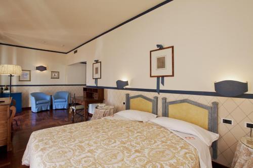 Relais Villa Pomela في نوفي ليغوري: غرفة نوم بسرير كبير وكراسي زرقاء