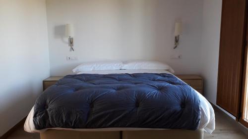 a bed with a blue comforter in a room at O Trancallo in Viana do Bolo