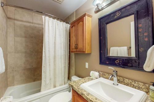 ein Badezimmer mit einem Waschbecken, einer Badewanne und einer Dusche in der Unterkunft Pinewood Getaway in Ketchum