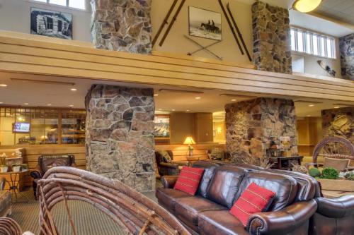 a living room with a leather couch and a stone wall at Shoshone 1960 in Big Sky