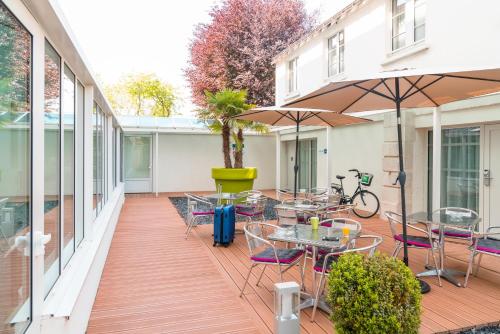 a patio with tables and chairs and an umbrella at ibis Styles Saumur Gare Centre in Saumur