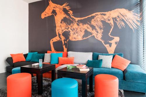 a living room with a couch with a horse on the wall at ibis Styles Saumur Gare Centre in Saumur