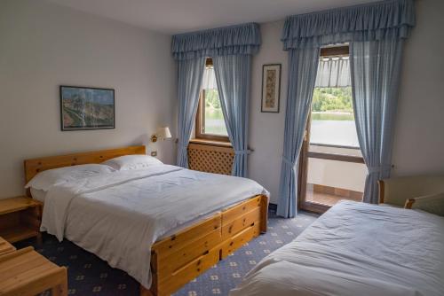 a hotel room with two beds and a window at Sporthotel Europa Sul Lago in Alleghe