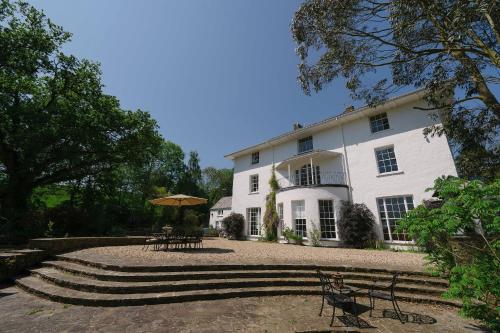 a large white building with benches and tables in front of it at Corffe House and Holiday Cottages in Barnstaple