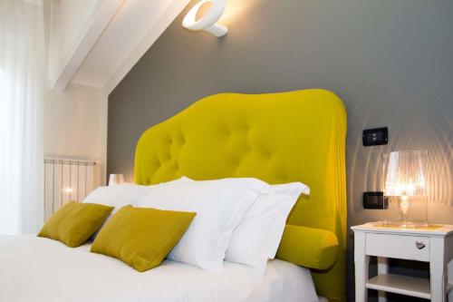 a bed with a yellow headboard in a bedroom at Pepe's Home B&B in Nichelino
