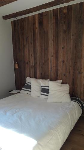 - un grand lit blanc avec un mur en bois dans l'établissement L'appartement d'Anna, à Annecy