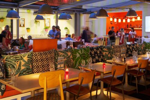 a restaurant with tables and chairs with people in the background at Mama Shelter Marseille in Marseille