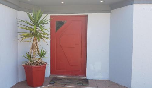 a red door with a plant in front of it at Eagle's Rest in Hartenbos