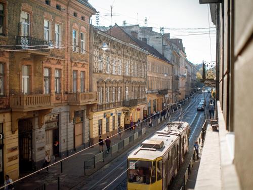 a yellow bus driving down a city street with buildings at Art Deco Central Rooms in Lviv