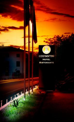 a sign in front of a building with a sunset in the background at Albergo Costantini in Tarcento
