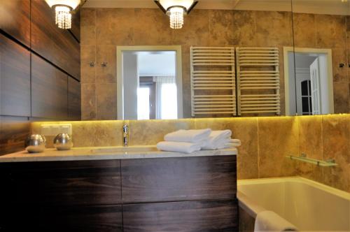 een badkamer met een wastafel, een bad en een spiegel bij Prudentia Apartments Wilanów in Warschau