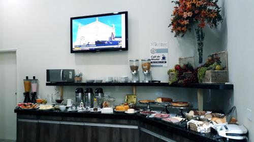 um buffet com comida e uma televisão na parede em Lodi Express Hotel em Arapongas